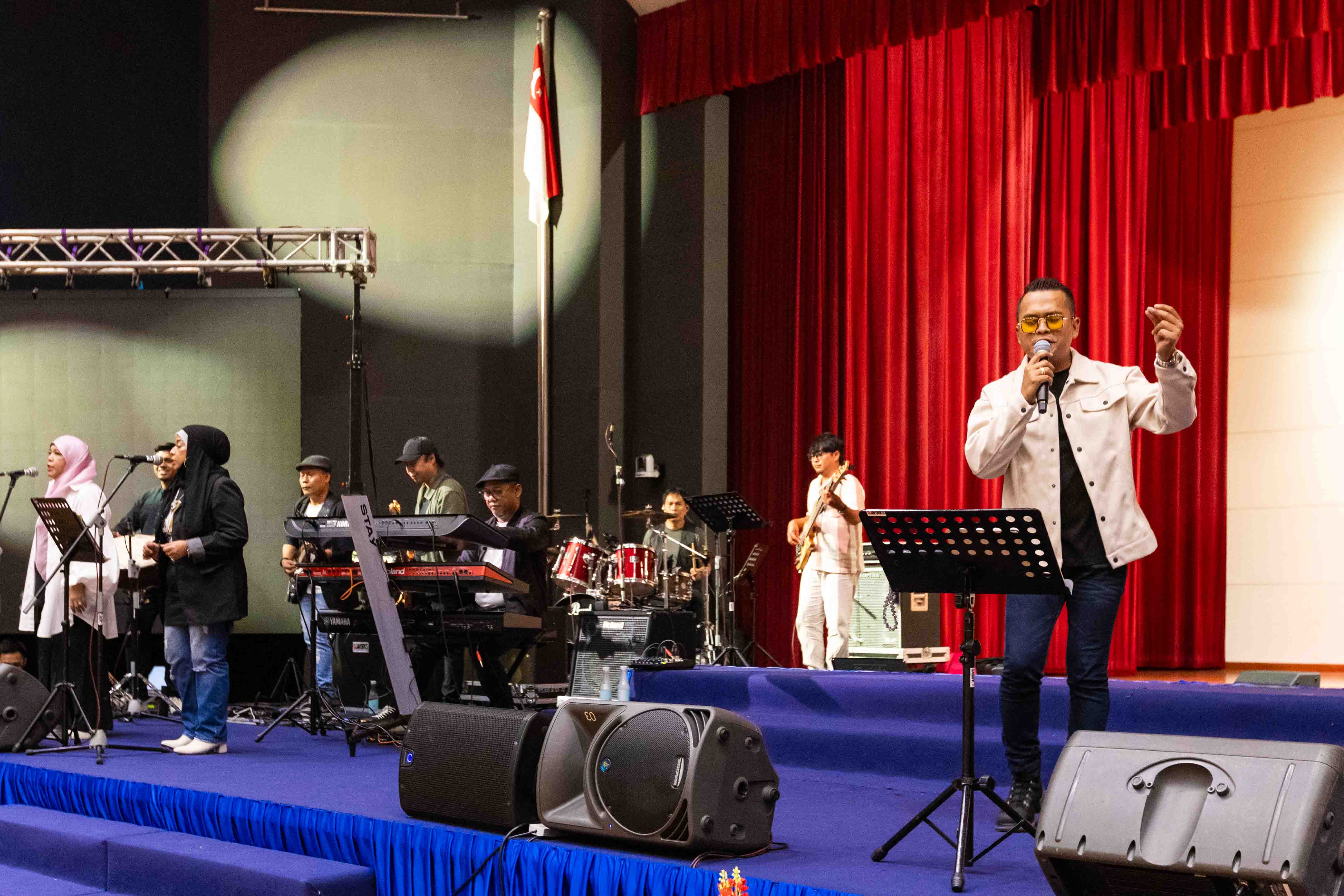 A singer performs on stage accompanied by a live band.
